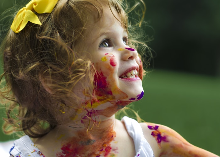 Yüzünde renkli boyalar olan gülümseyen çocuk
