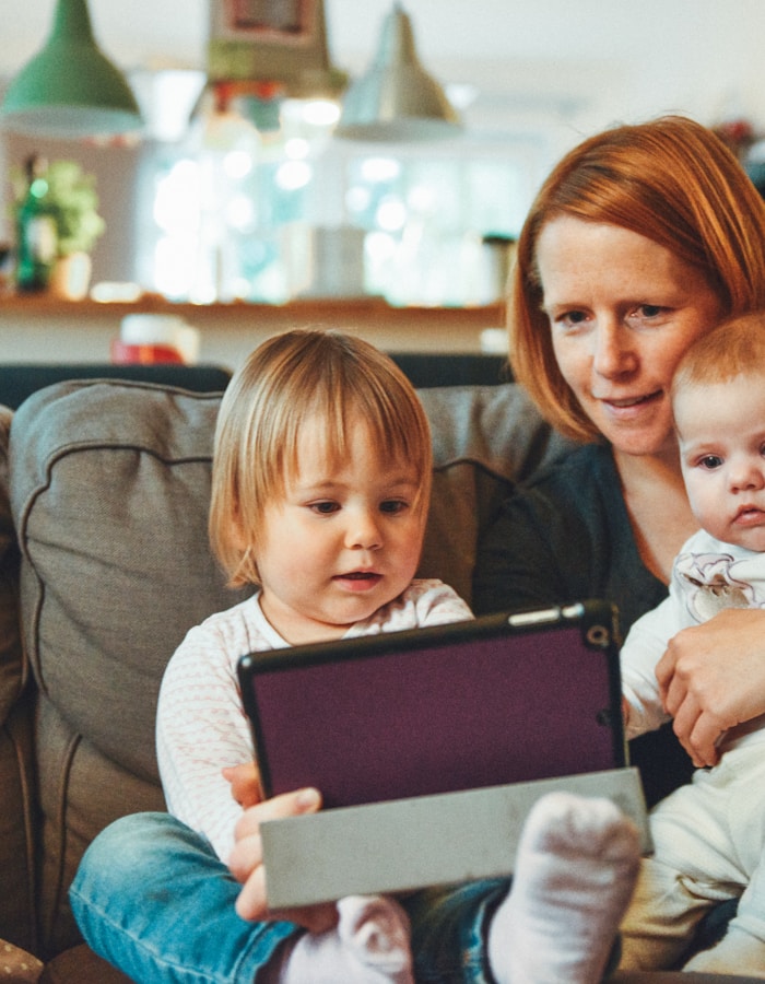 Bir yetişkin ve iki çocuk birlikte tablet kullanıyor